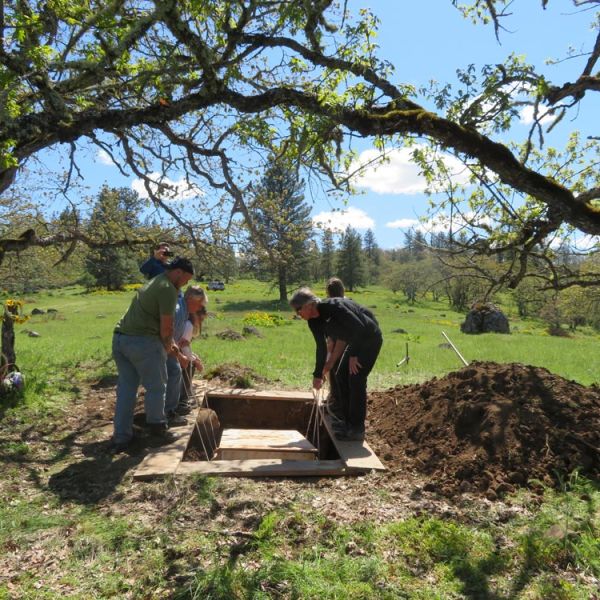 family and friends lower casket into natural burial site grave