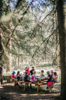 summer camp children making nature crafts at picnic table